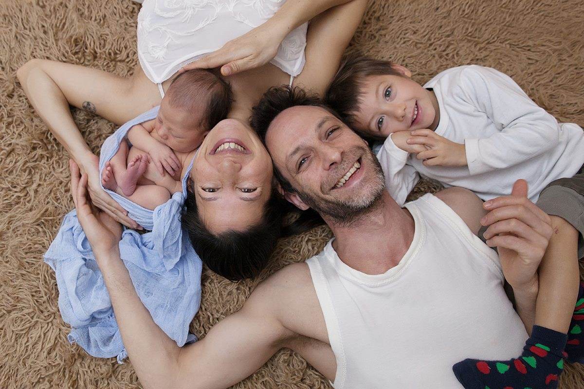 La famille réunie en rond sur un tapis douillet, tout sourire : Caro, Philippe et leurs deux garçons
