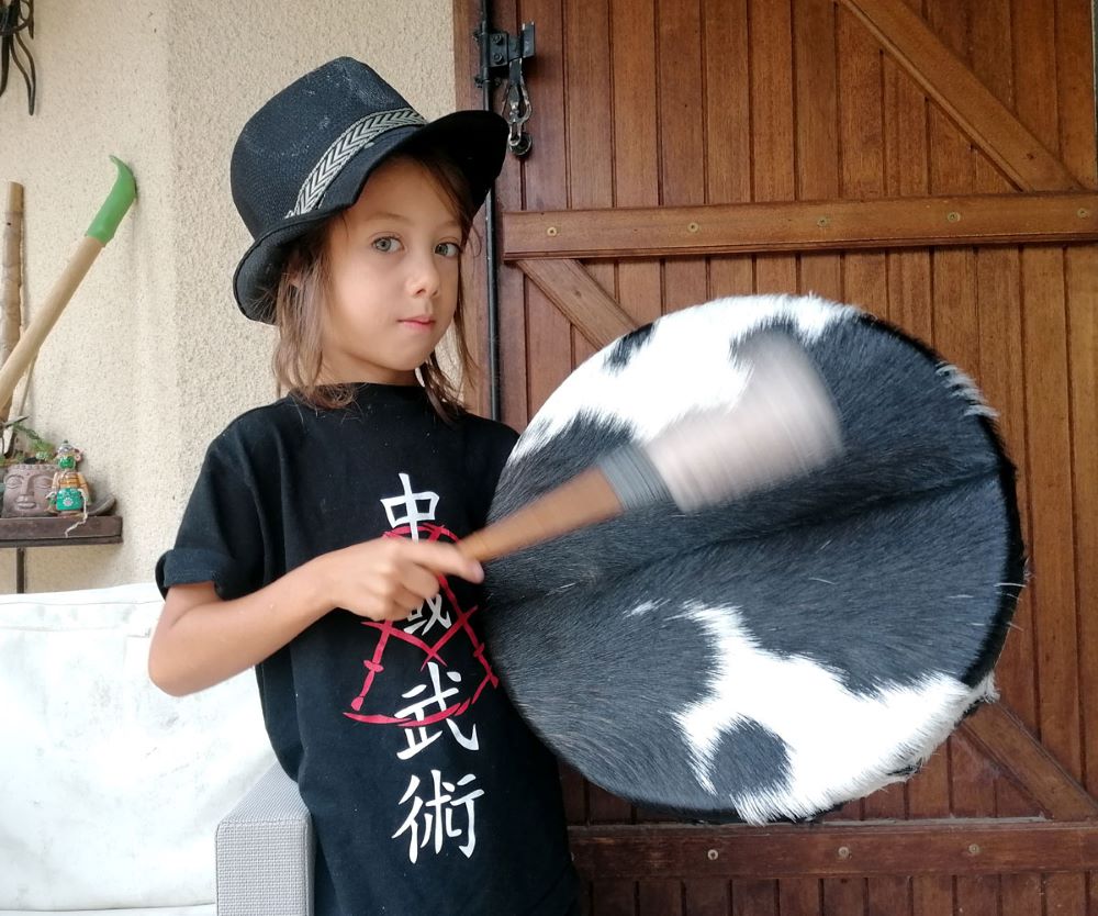 Un enfant joue d'un tambour à peau de vache